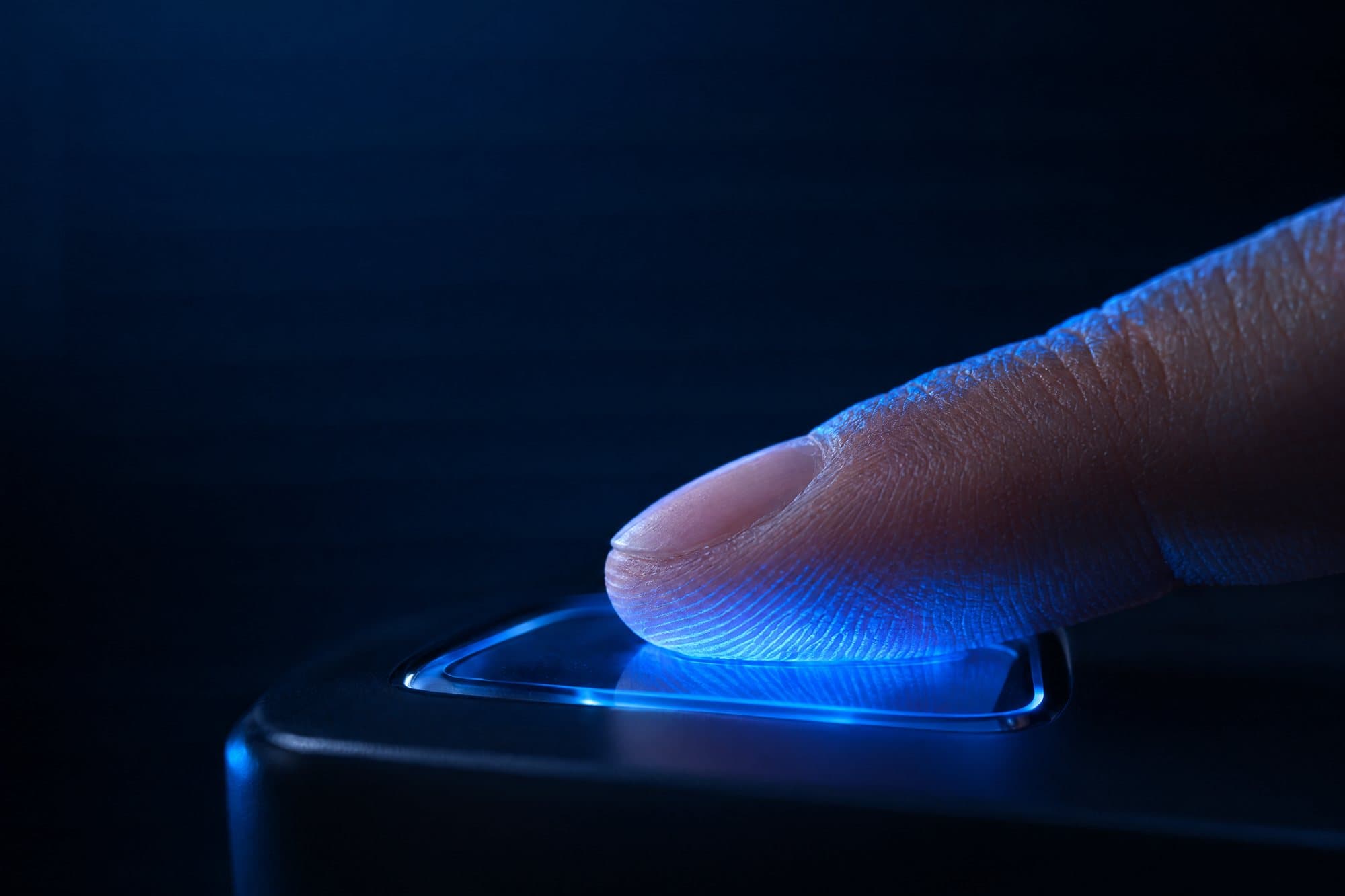 Dedo sobre leitor óptico de impressão digital iluminado em azul